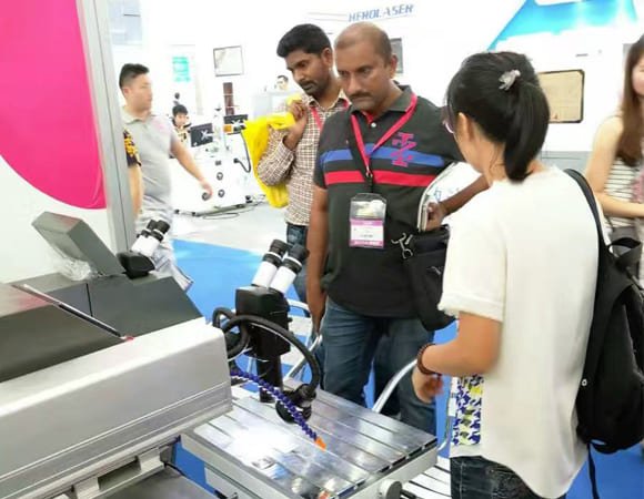Customers examining Fixonlaser precision welding equipment at international trade show, discussing laser welding solutions for mold repair and jewelry manufacturing
